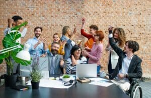 Entrepreneurs working on project indoors in office, celebrating successful contract.