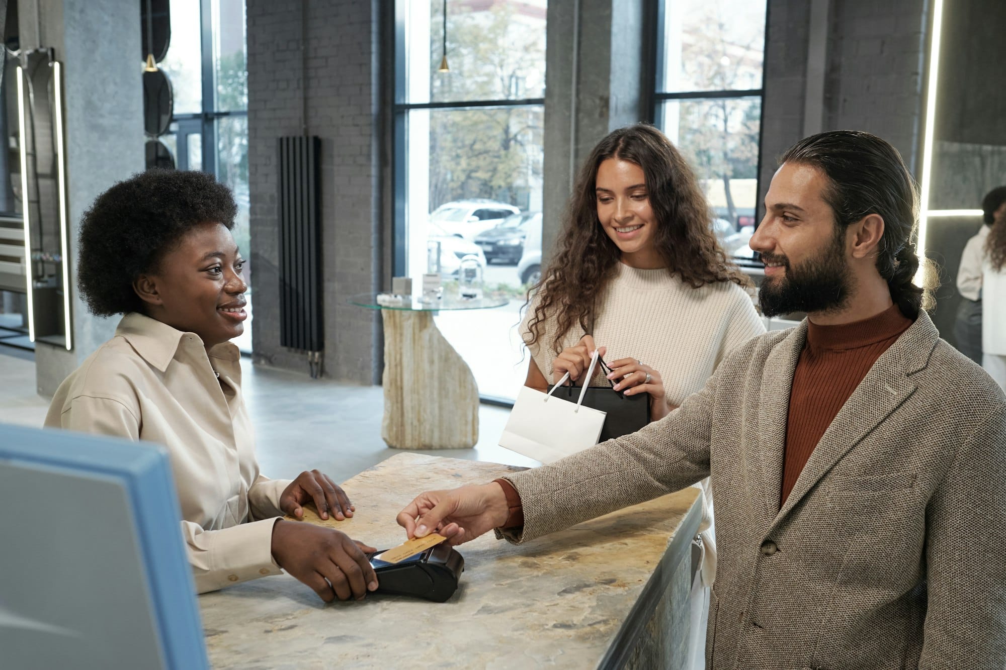 Happy young female shop assistant serving male client